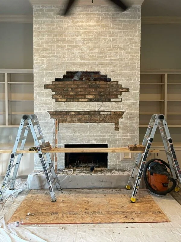 Fireplace renovation with brick wall, ladders, tools, and ceiling fan in progress – Texas Chimney LLC