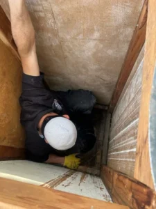 Person inspecting wooden enclosure interior for chimney work