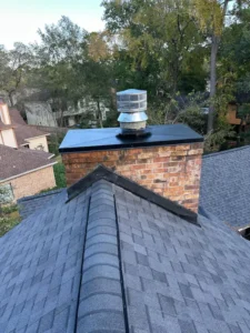 View of a chimney from the roof showing new black top and screened metal vent
