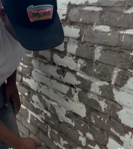 Technician working on chimney mortar repair at a home, applying new mortar on the brickwork.