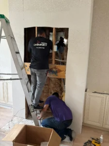 two workers performing fireplace or chimney repair/installation services.