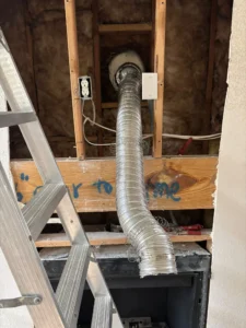 an installation of a flexible aluminum duct, most likely for a dryer or HVAC system, within a framed wall.