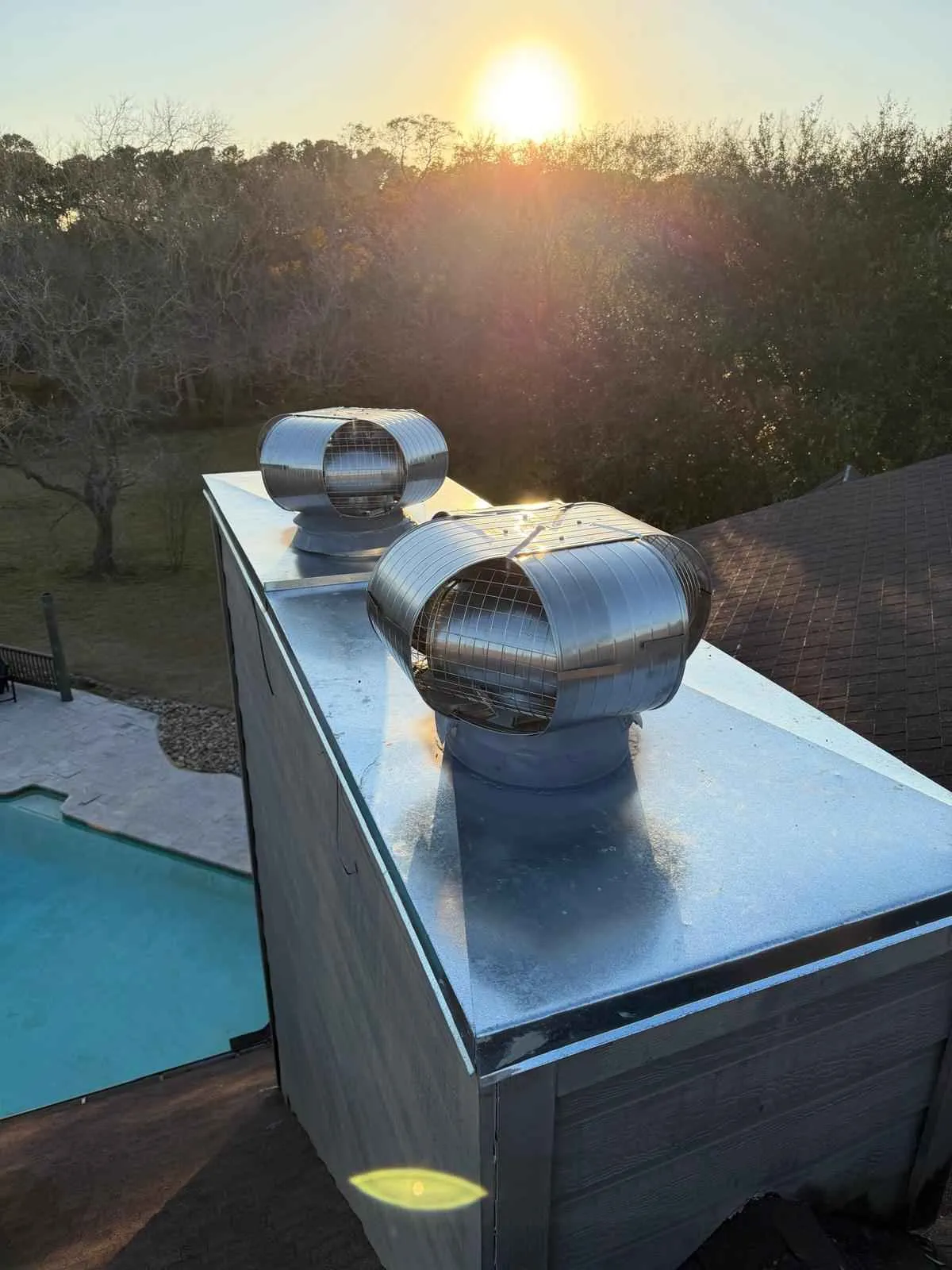 wind-driven turbine roof ventilators (also known as whirlybirds) installed on a metallic chimney cap