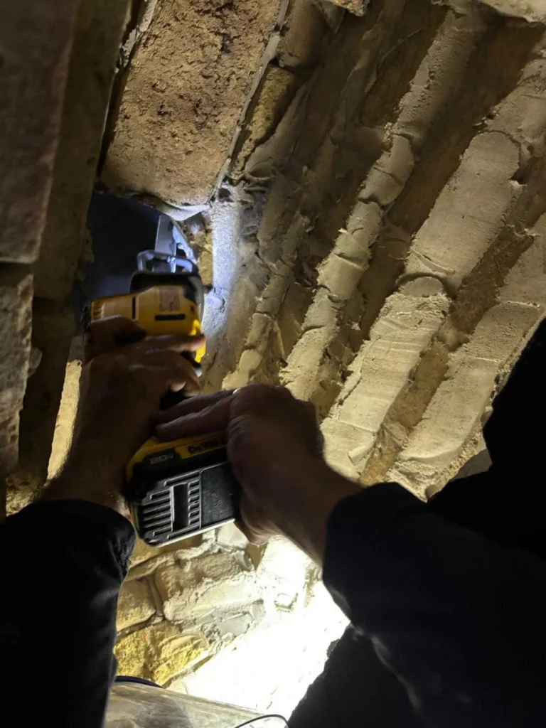 a person using a DeWalt cordless power drill to bore into a masonry wall.
