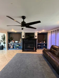 a living room with a black fireplace surround and hearth, flanked by built-in shelving and cabinetry