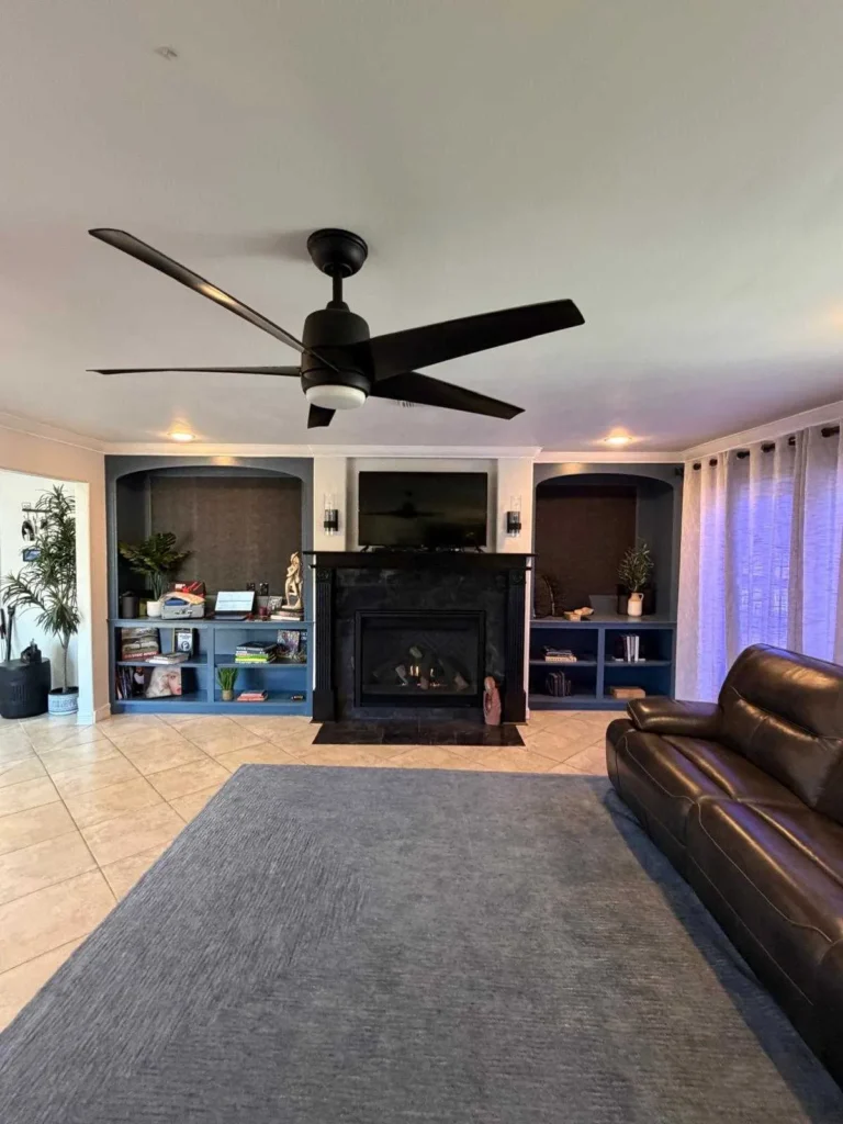 a living room with a black fireplace surround and hearth, flanked by built-in shelving and cabinetry