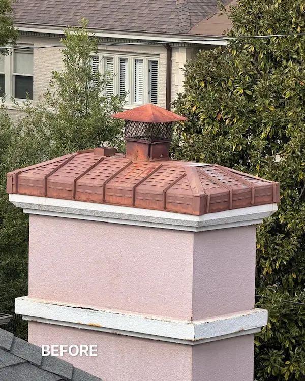 Medium shot of a light-colored stucco chimney topped with a rusted red-brown clay cap. Green foliage and a building are in the background. The text 'BEFORE' is in the bottom-left corner.